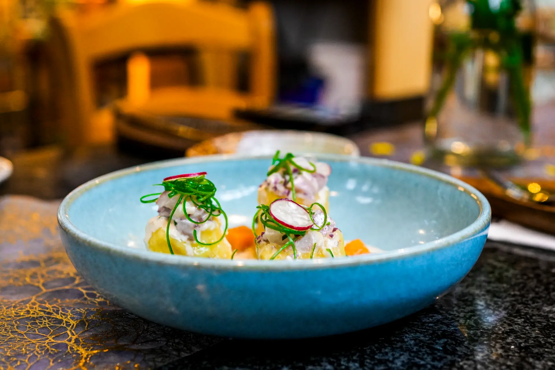 Ceviche served in a pale blue bowl with radish and herbs