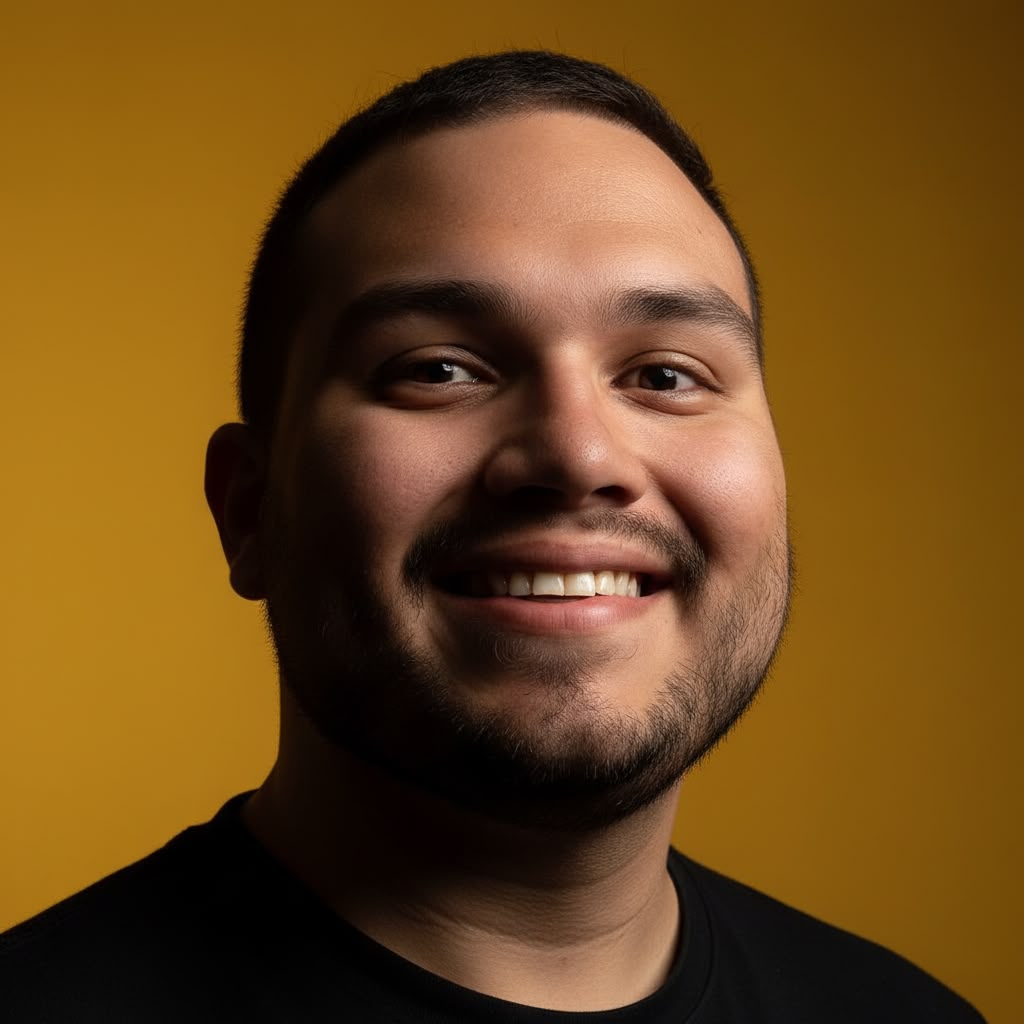 Portrait of Juan Pablo Arce smiling against a warm yellow backdrop