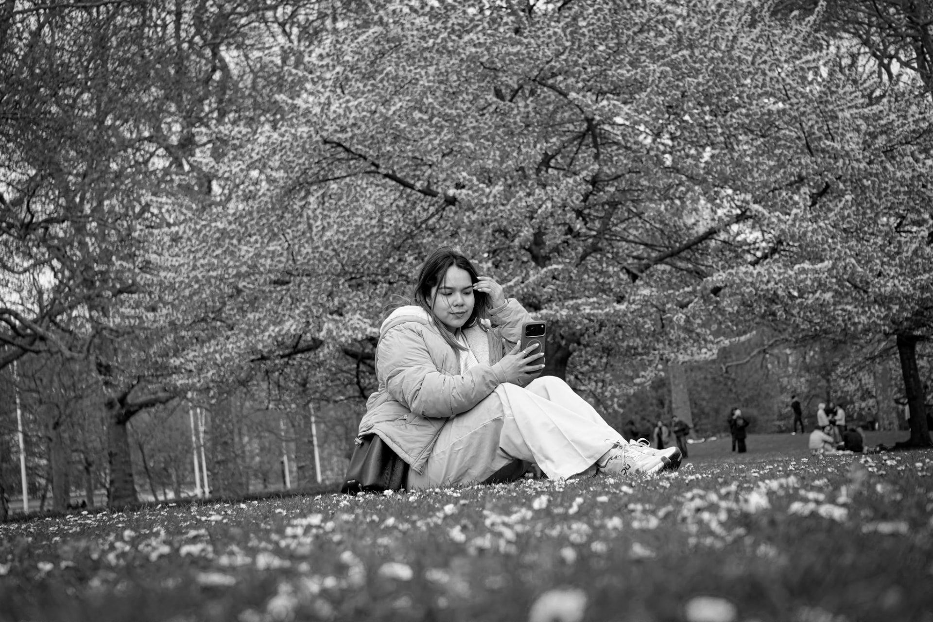María José Ospina sitting under blossom trees in a London park, black and white photograph