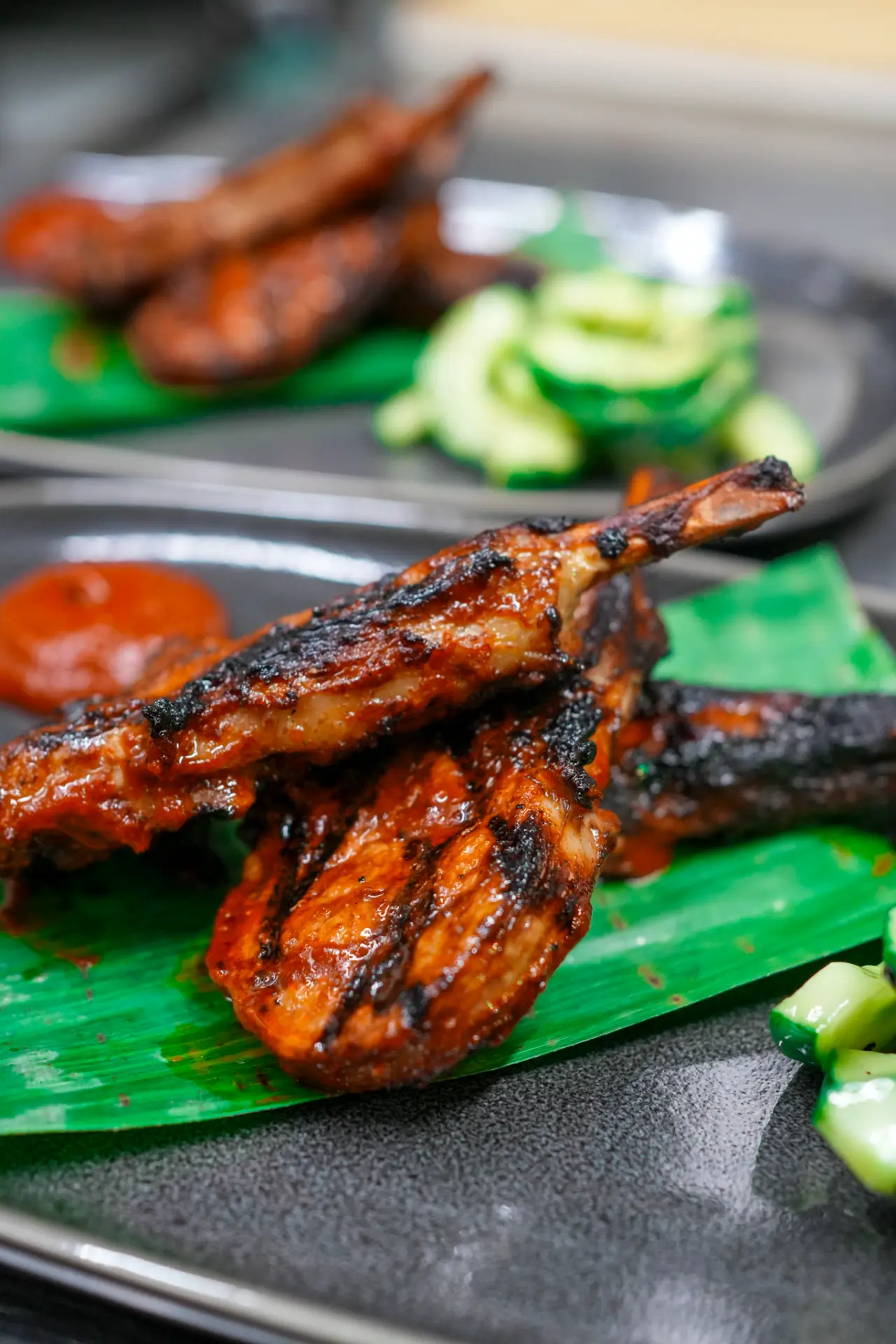 Charred lamb chops from Colibrí served on banana leaf with cucumber and chilli sauce