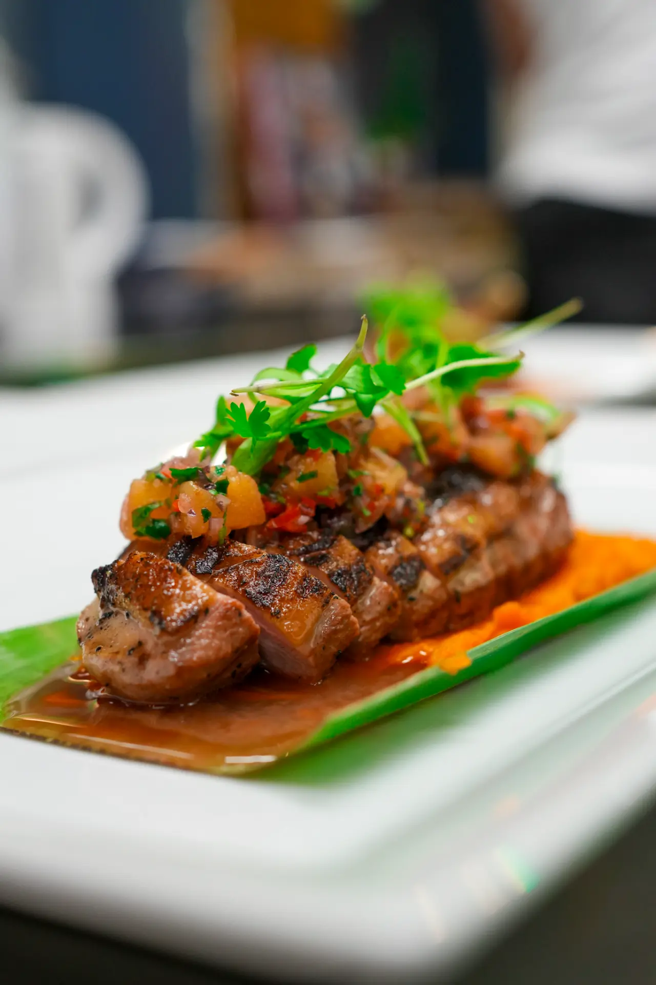 Smoked duck from Colibrí sliced over banana leaf with fruit salsa and orange purée